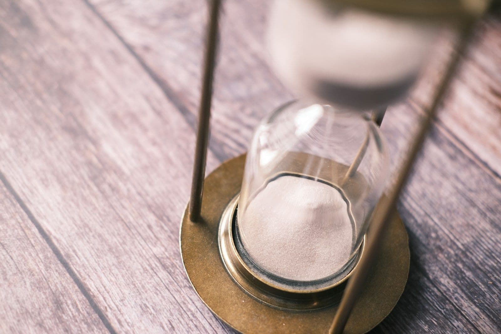Hourglass on wooden table with sand running out, representing an expiring electricity contract deadline
